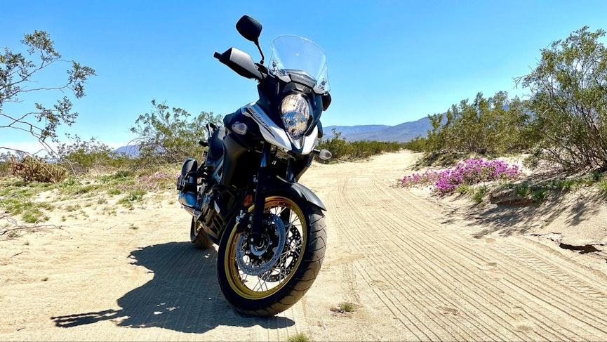 2023 Suzuki V-Strom 650XT parked on sand next to a sand roadway